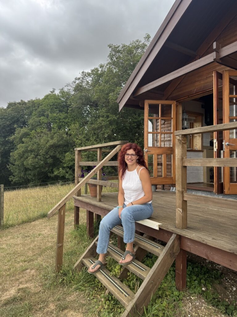 Chloe seated on the steps outside a wooden cabin
