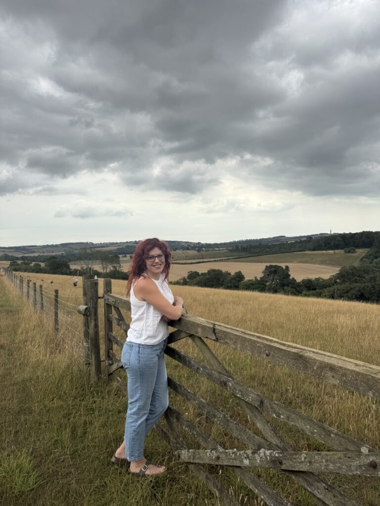 Chloe standing beside a field gate in the countryside