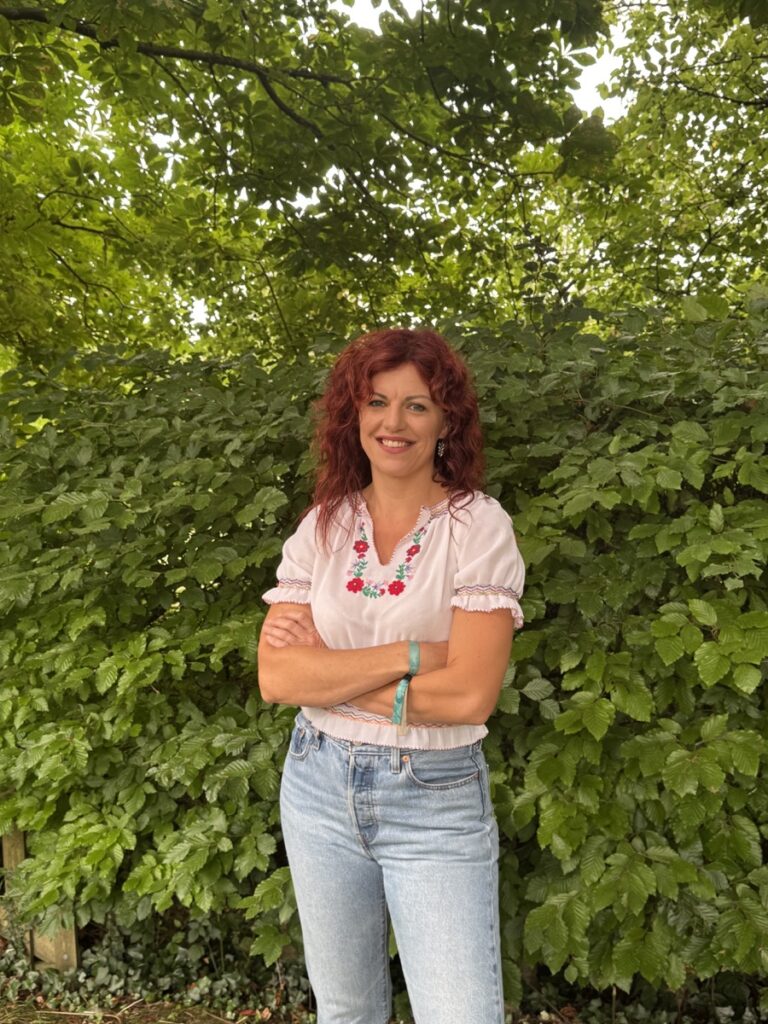 resonate-chloe-woodland-portrait Chloe standing outdoors in front of leafy woodland